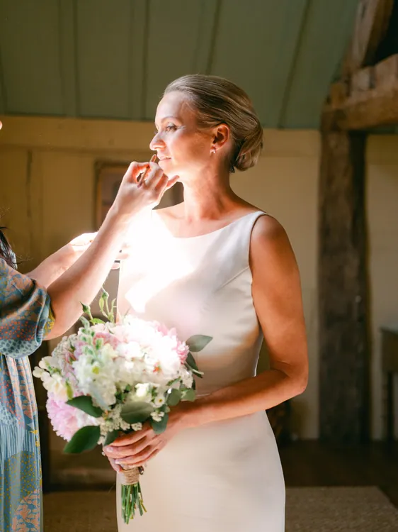 Bride holding a bouquet with her blonde hair in a polished updo - Photography by Faye Taylor